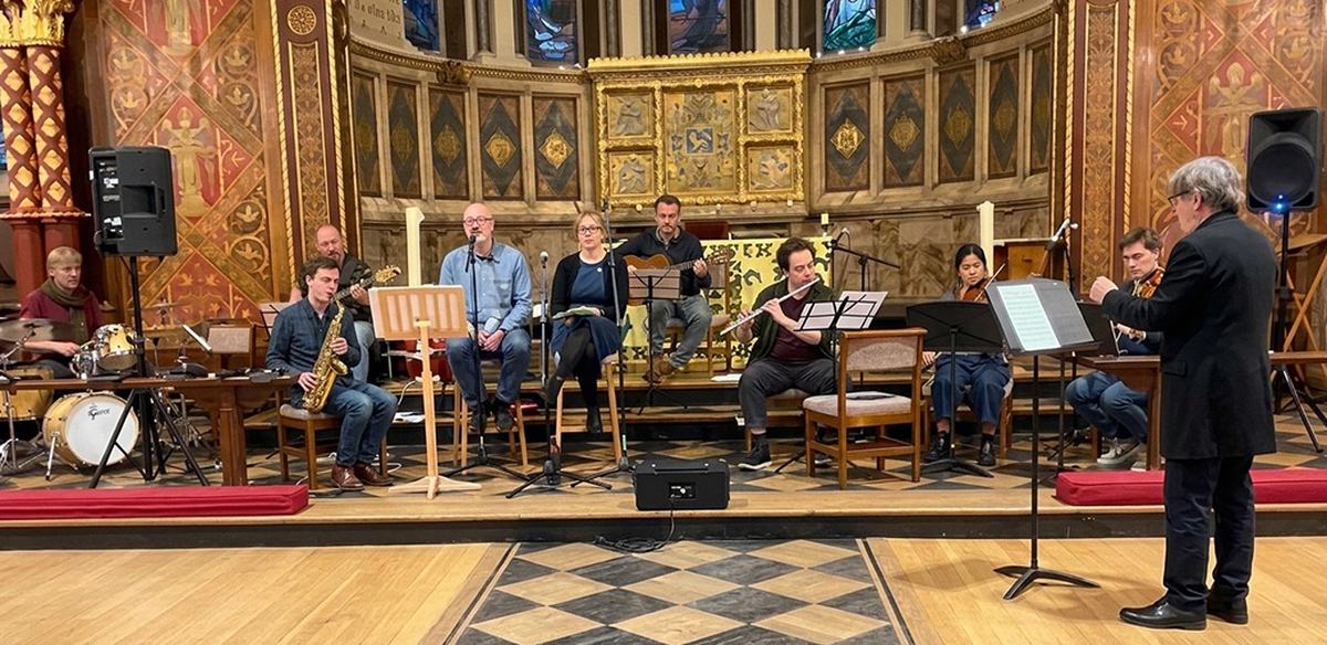 Band, flute and strings on stage at the Chapel of King&rsquo;s College London, with David Treece conducting