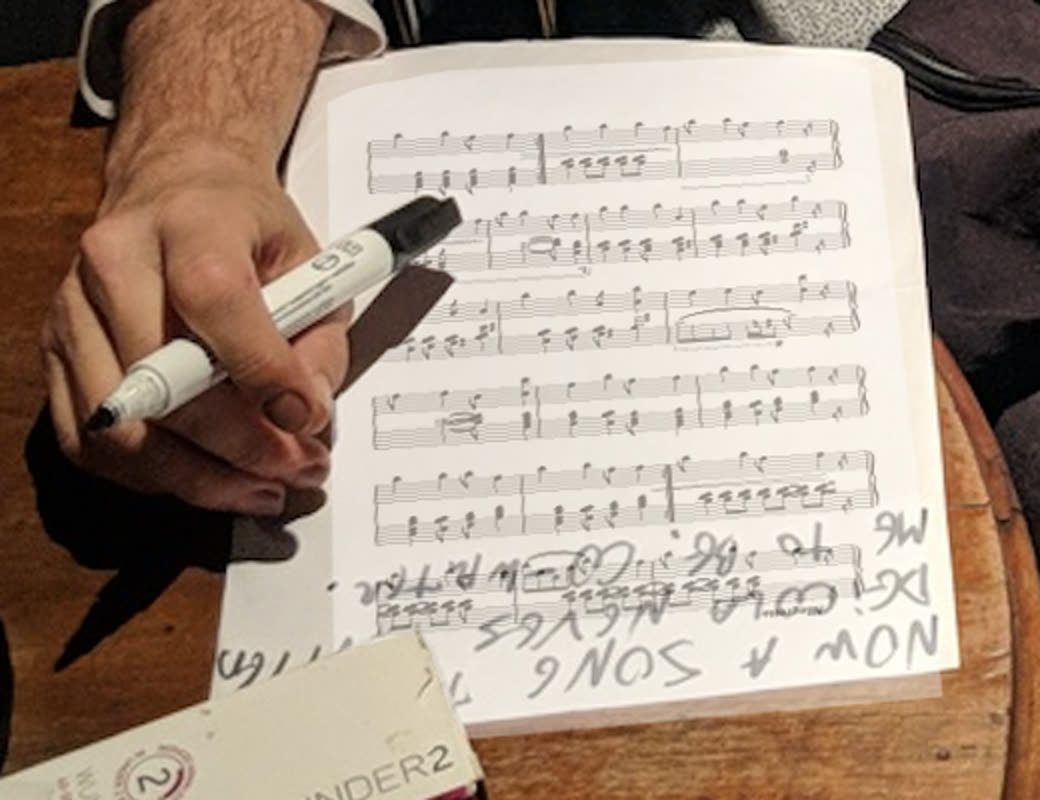 Gui Tavares writing on handwritten manuscript paper with a marker
